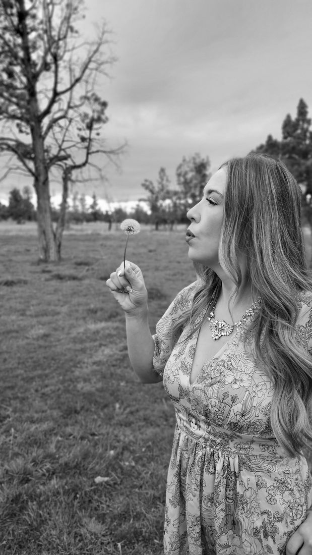 Black and white portrait of Aliki blowing a dandelion